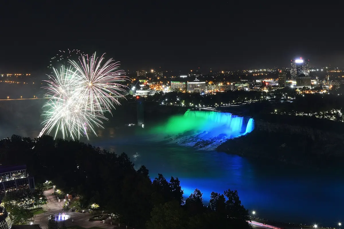 Fireworks over Niagara Falls with the falls lit in blue and green