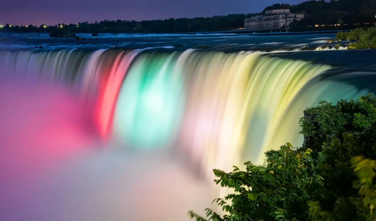 Horseshoe Falls illuminated in pink, teal and yellow at night
